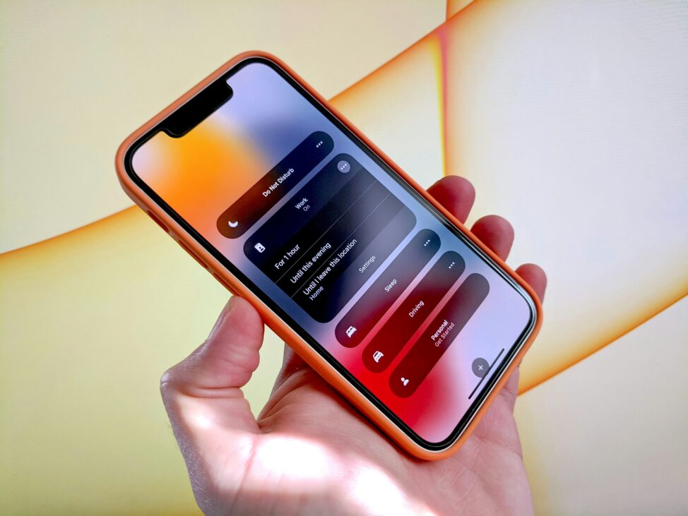 An individual grasping an iPhone X, displaying a 'Do Not Disturb' notification on the device.